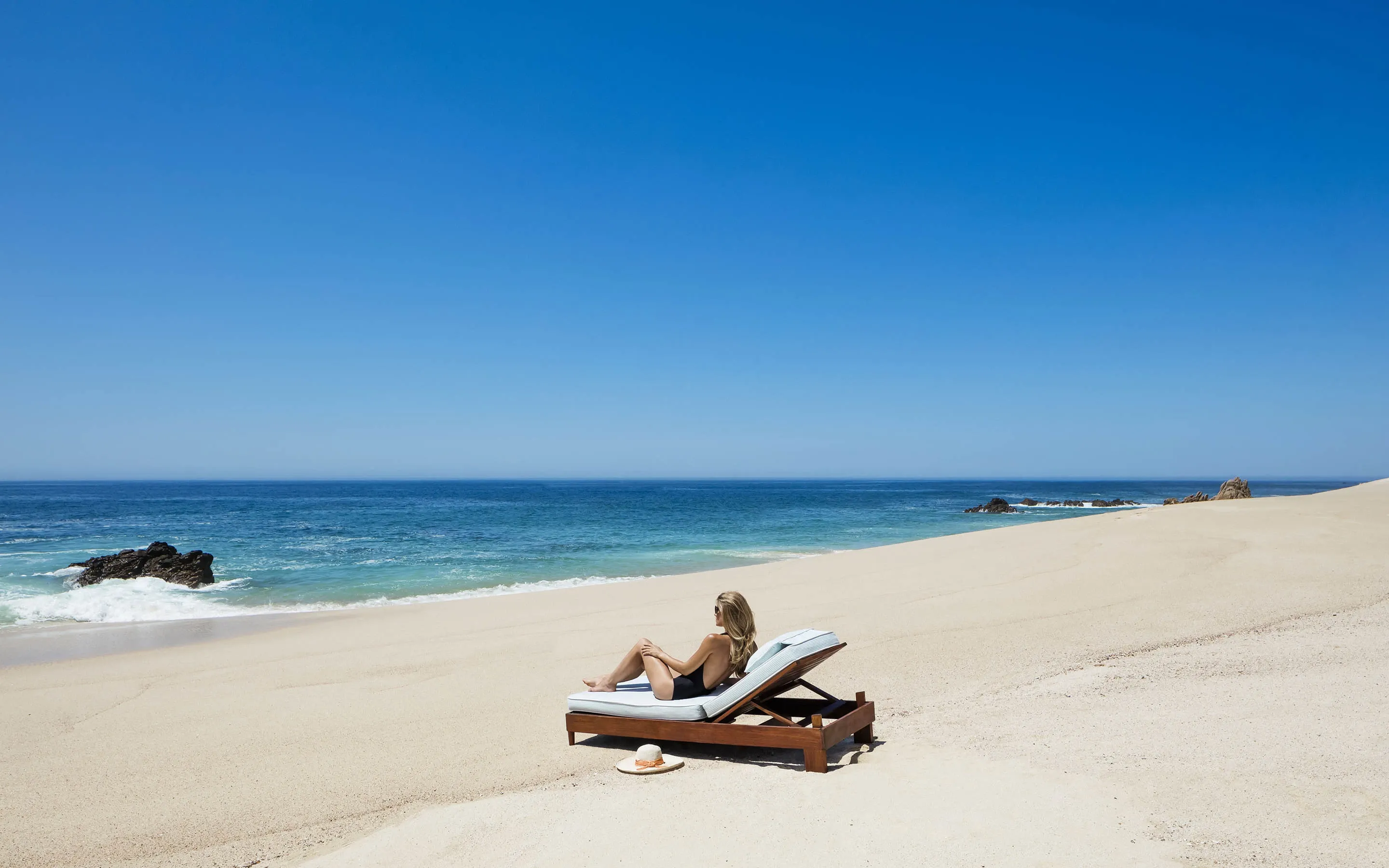 A woman sitting on a sunbed at the beach at One&Only Palmilla