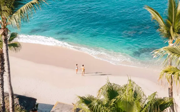 A man and a woman holding hands at the beach of One&Only Palmilla