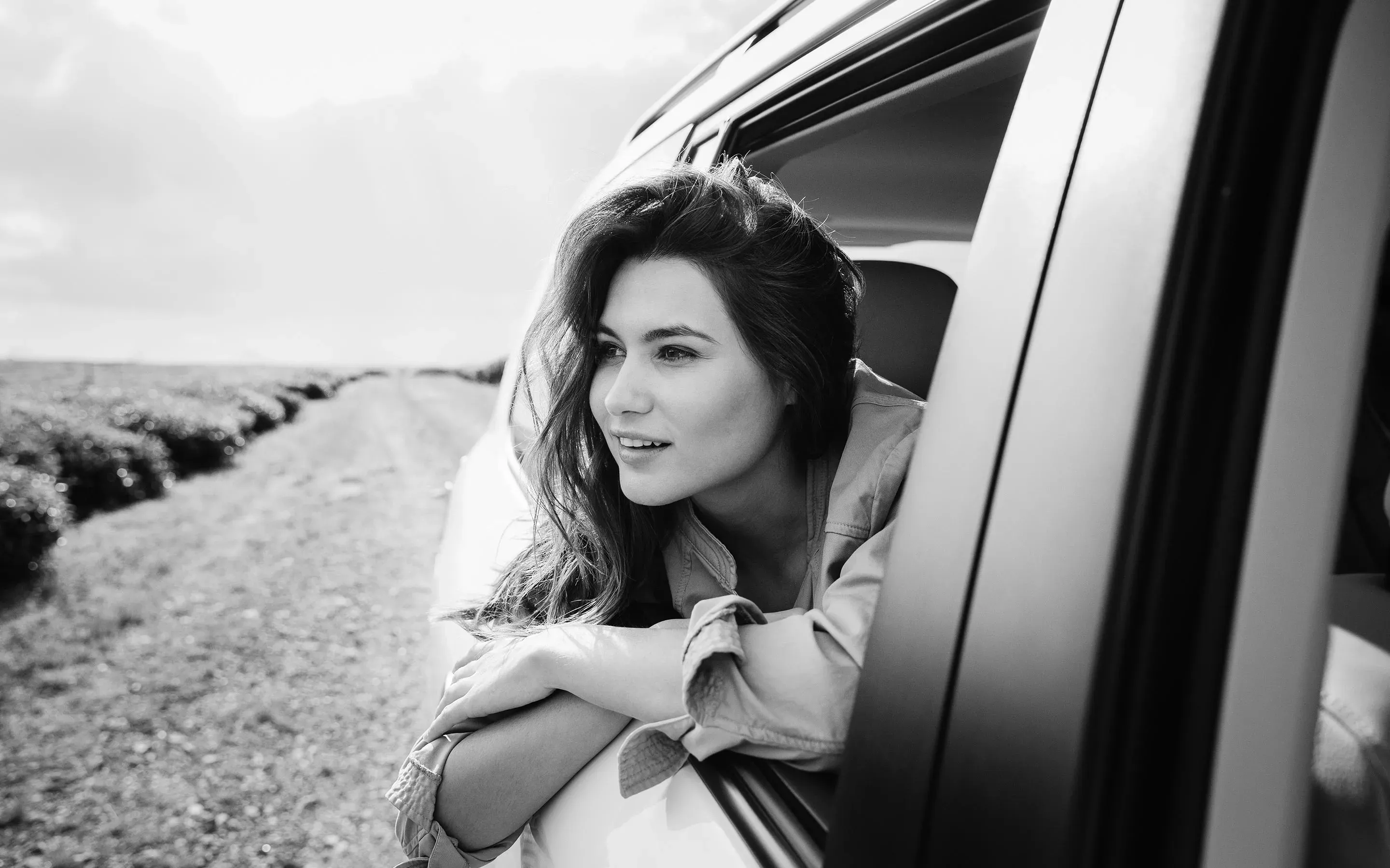 A woman leaning out of a car window, enjoying the breeze and the view