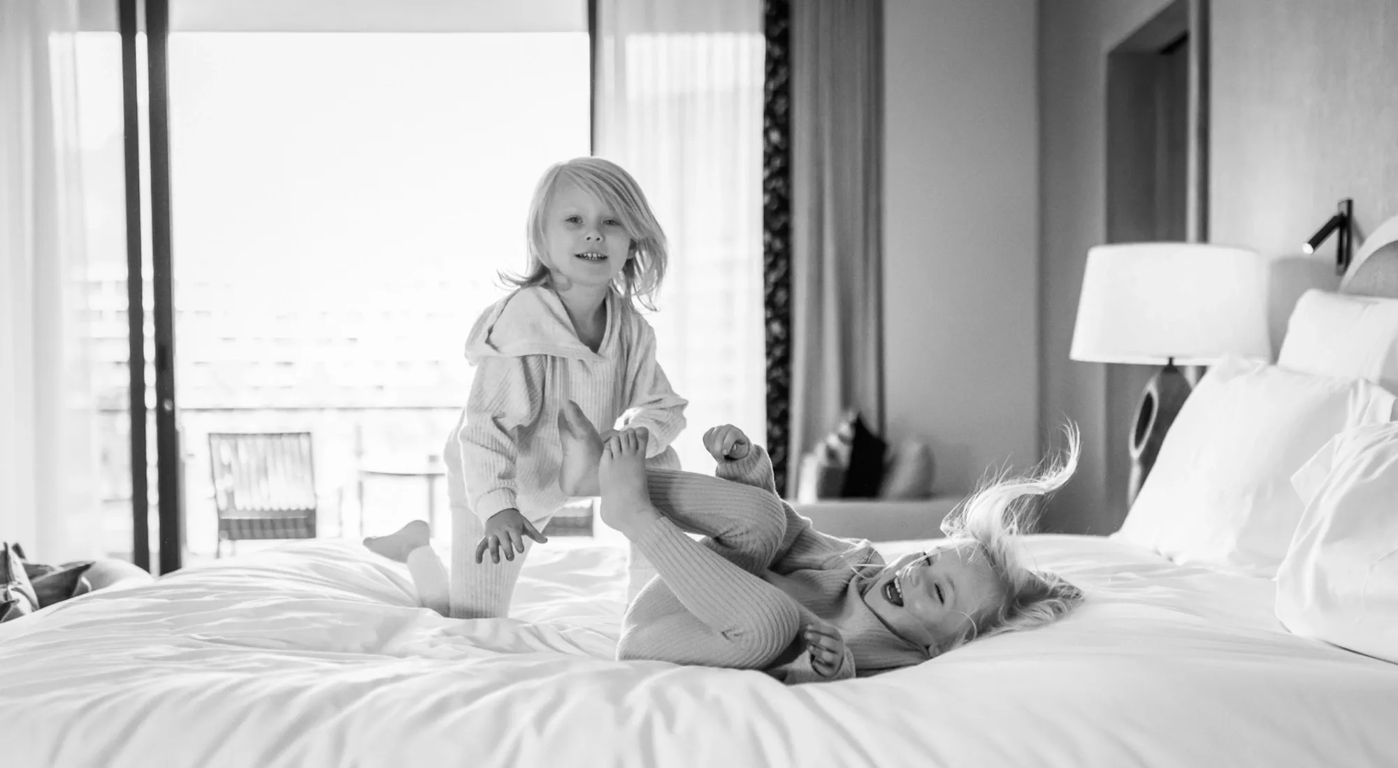 Two girls playing on the bed at One&Only Cape Town