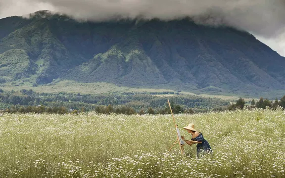 A woman painting the view of mountains at One&Only Gorilla's Nest