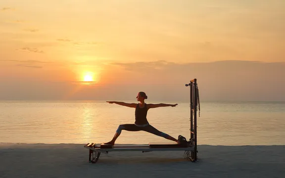 A woman practicing Yoga by the Ocean at One&Only Reethi Rah