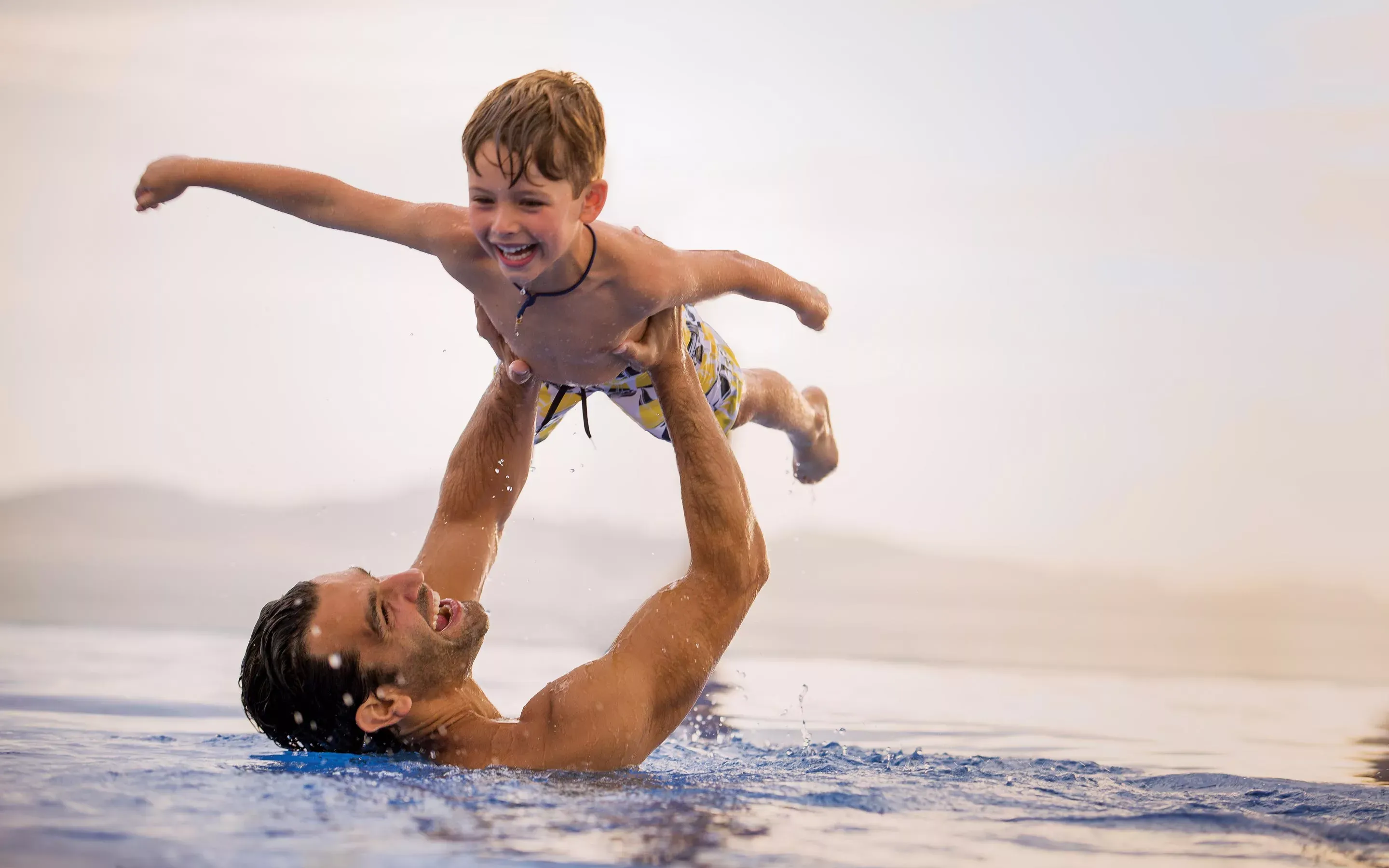 Man holding a kid in the water at One&Only The Palm