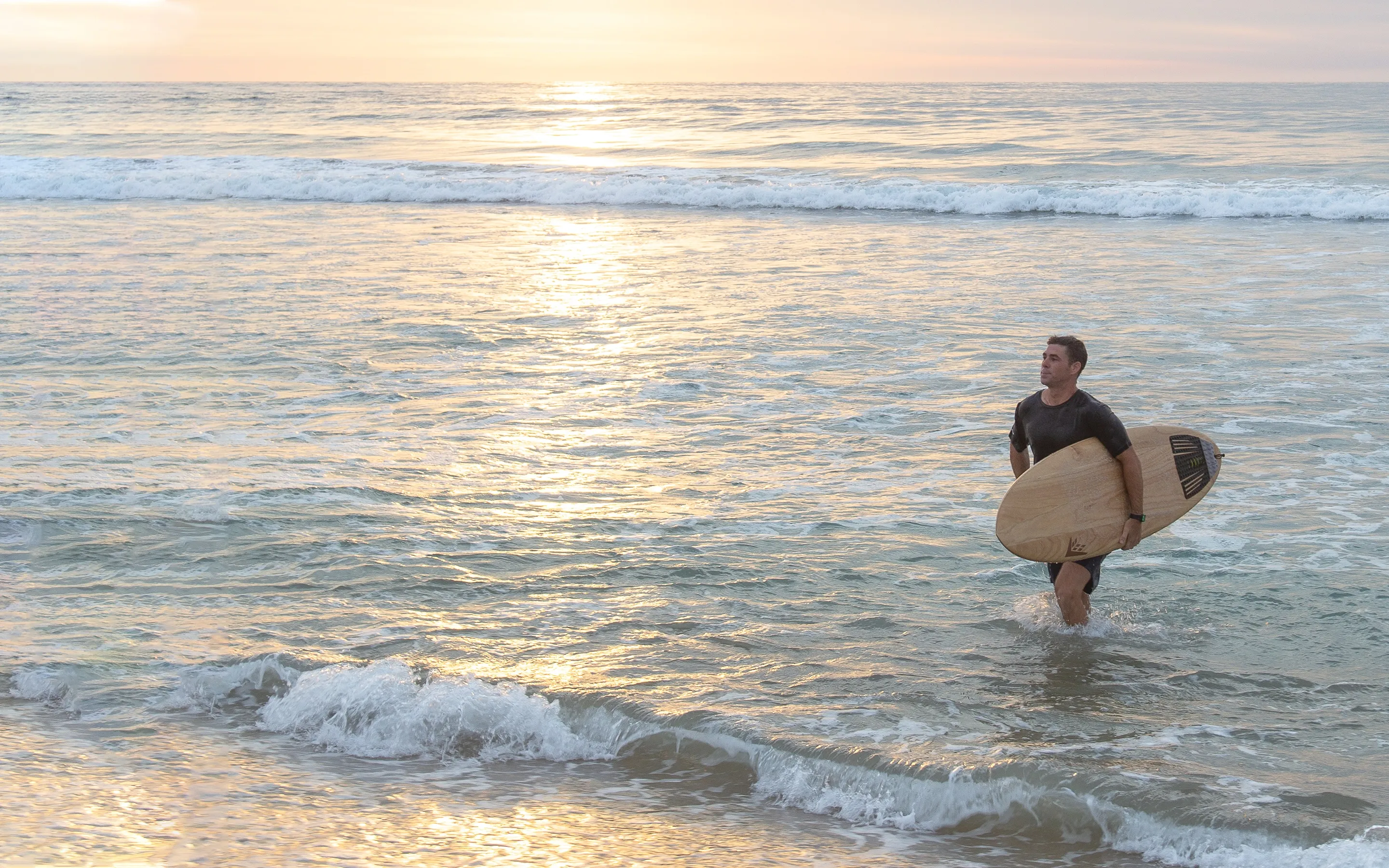 Man carrying a surfboard in the sea at One&Only Palmilla