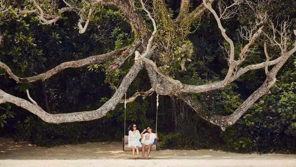 Couple sitting on a swing under a majestic tree at One&Only Resort
