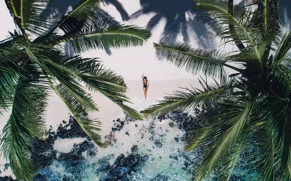 Aerial view of a woman sunbathing between palm trees at One&Only Le Saint Géran